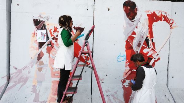 In this Thursday, Aug. 20, 2015 photo, independent Afghan artists paint on a barrier wall which blocks a main gate of the presidential palace in Kabul, Afghanistan. (File photo)