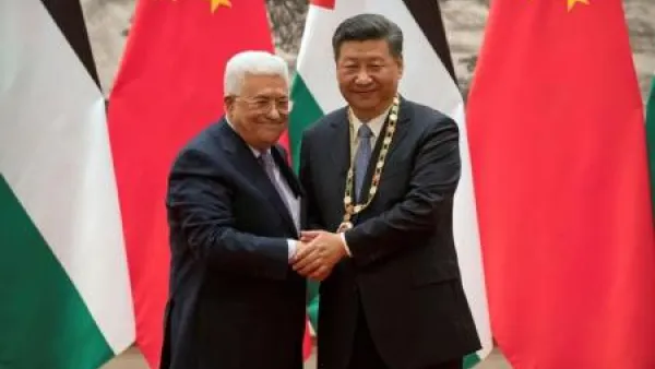 الرئيس الفلسطيني محمود عباس (يسارا) يصافح نظيره الصيني شي جين بينغ في بكين يوم الثلاثاء
