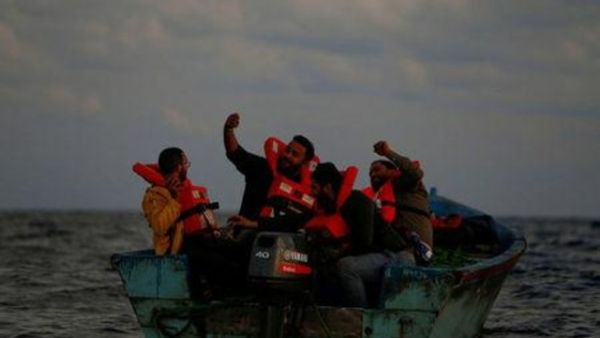 مهاجرون ليبيون على قارب خشبي يحتفلون ويتخذون صورة سيلفي أثناء إنقاذهم
