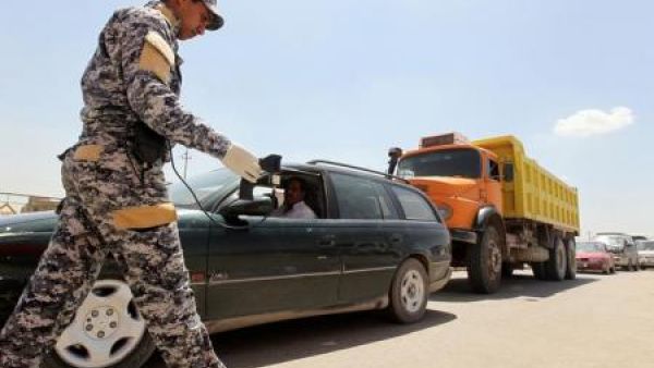 شرطي يستخدم جهاز رصد متفجرات يفحص حافلة عند مدخل مدينة الصدر في بغداد
