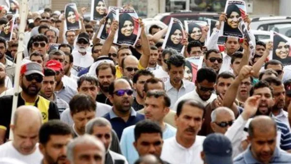 مشيعون يحملون صور المرلأة التي قتلت في حادث يوم الجمعة في المنامة عاصمة البحرين في جنازتها بقرية السترة يوم السبت
