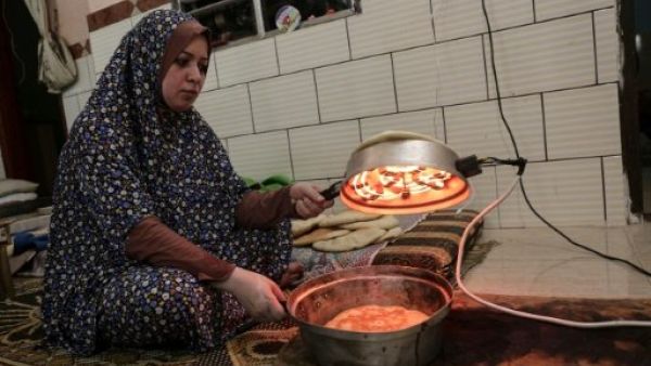 فلسطينية تعد الخبز مستفيدة من ساعات الكهرباء القليلة التي تصل المنازل يوميا في مخيم رفح للاجئين في غزة

