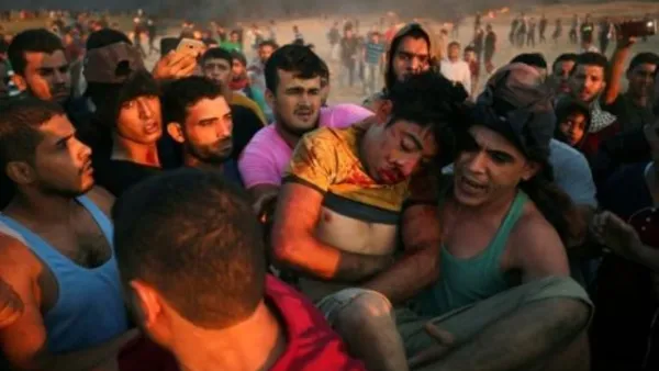 فلسطينيون يحملون فتى أصيب بجروح خلال مواجهات على السياج الفاصل بين إسرائيل وقطاع غزة
