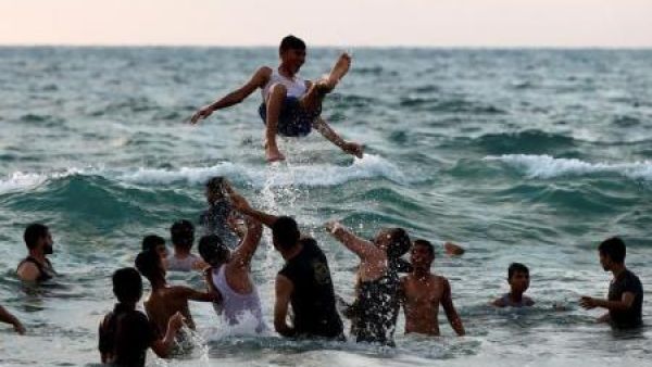 فلسطينيون يلهون في البحر على شاطئ قطاع غزة
