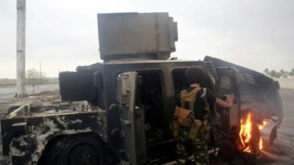 متمرد حوثي يتفقد مدرعة أصيبت في غارة جوية

