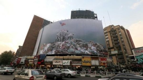 إيرانيون يمرون بسياراتهم من أمام لافتة منهاضة للولايات المتحدة في طهران
