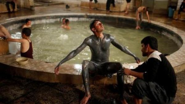 عراقي يغطي ابنه بالرمل من بركة كبريت في حمام العليل
