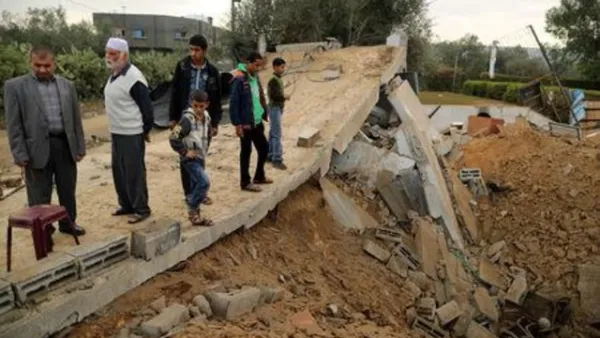 فلسطينيون يقفون على أنقاض مبنى دمرته غارة جوية إسرائيلية في خان يونس

