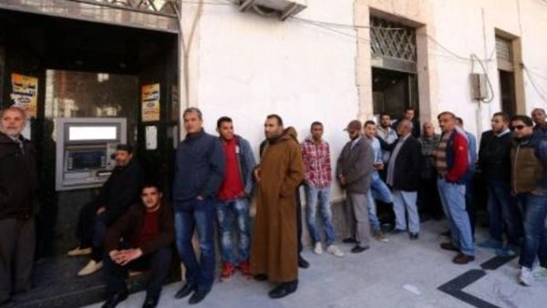 ليبيون ينتظرون بالدور لسحب أموال من جهاز صراف آلي أمام أحد المصارف في طرابلس 
