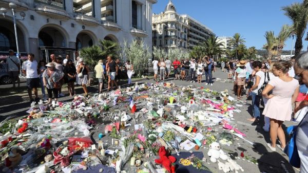 People gather near flowers placed at a makeshift memorial near the Promenade des Anglais in Nice on July 17, 2016, in tribute to the victims of the Bastille Day attack that left 84 dead. (AFP/Valery Hache