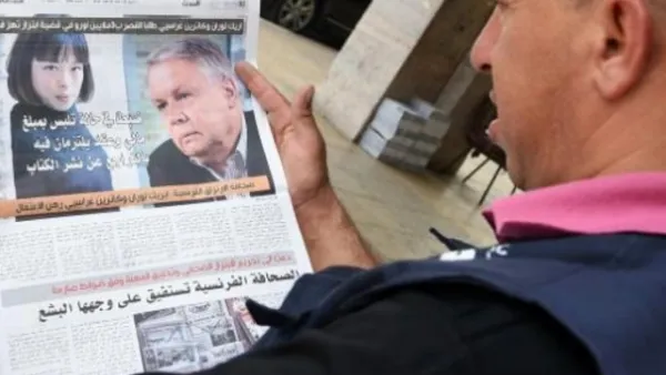 مغربي يقرأ خبرا في صحيفة حول اتهام صحافيين فرنسيين بابتزاز ملك المغرب
