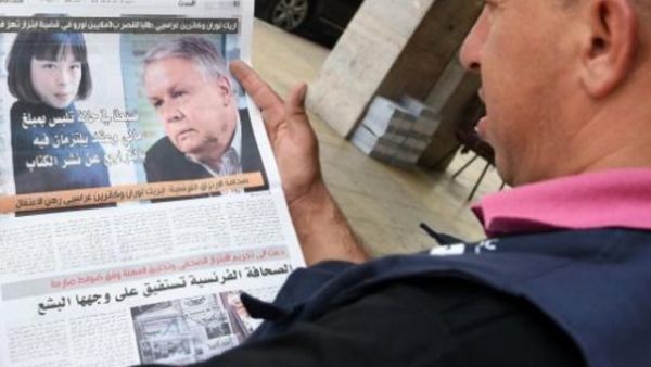 مغربي يقرأ خبرا في صحيفة حول اتهام صحافيين فرنسيين بابتزاز ملك المغرب
