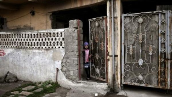 طفلة تطل خلف بوابة في الموصل خلال عملية للقوات العراقية لاستعادة الجزء الغربي للمدينة من الجهاديين


