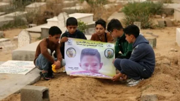اصدقاء الفتى الفلسطيني محمد ايوب الذي قتل برصاص القوات الاسرائيلية على الحدود بين غزة واسرائيل يحملون صورته فوق قبره في بيت لاهيا في شمال قطاع غزة
