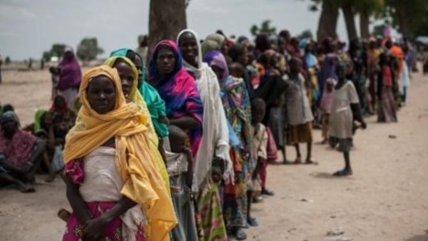 نساء واطفال ينتظرون في طابور امام عيادة ليونيسيف في مخيم عشوائي يأوي
