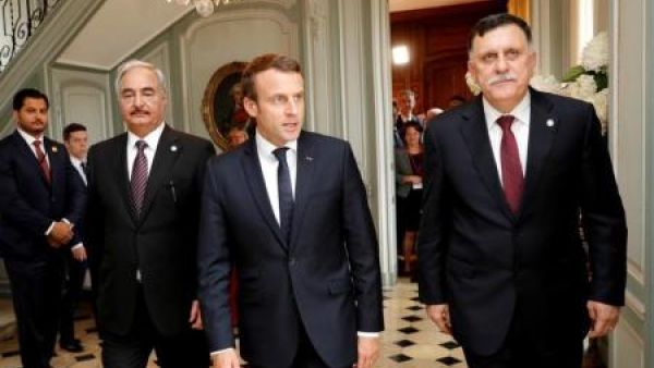 الرئيس الفرنسي إيمانويل ماكرون (في المنتصف) وإلى يساره حفتر وإلى يمينه السراج قرب باريس يوم الثلاثاء
