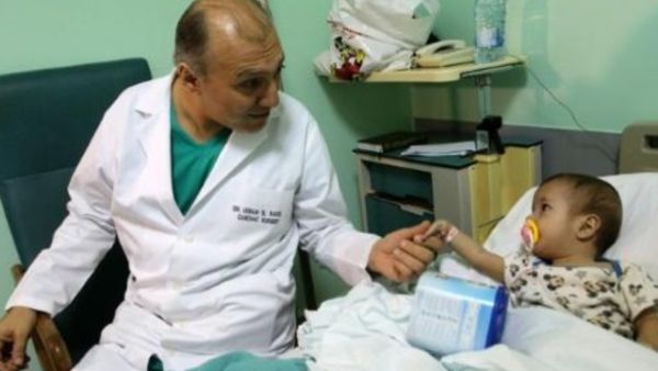 الدكتور عصام الراسي يمسك يد الطفلة السورية امينة حلو قبل اجراء جراحة لها في القلب في مستشفى حمود في صيدا


