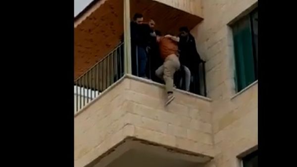 صورة من الفيديو تظهر اشخاصا يمنعون الطالبة من القاء نفسها من مبنى داخل الجامعة
