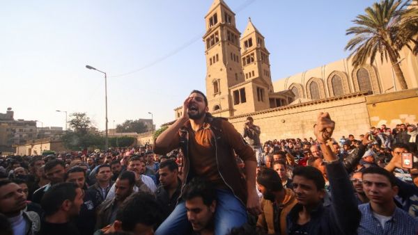 Egyptians shout slogans as they gather outside the the Saint Peter and Saint Paul Coptic Orthodox Church in Cairo's Abbasiya neighborhood after it was targeted by a bomb explosion on December 11, 2016. (AFP/Mohamed Muteab)