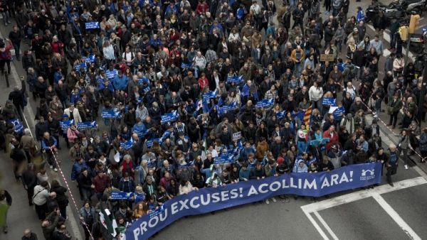 Tens of thousands of people march holding a banner reading "Enough excuses! Let's welcome them now" in a street of Barcelona during a pro-refugee demonstration on February 18, 2017. (AFP/Josep Lago)