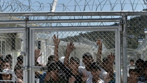 Young migrants and refugees stand at a fence of the Moria detention centre during a visit of Pope Francis in Mytilene, on 16 April, 2016. (AFP/File)