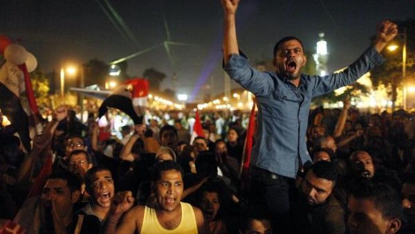 Egyptian protesters calling for the ouster of President Mohamed Morsi react as they watch his speech on a big screen (Mahmud Khaled / AFP)