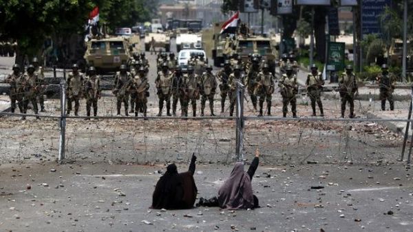 Egyptian supporters of deposed president Mohamed Morsi sit in front of barbed wire fencing that blocks the access to the headquarters of the Republican Guard in Cairo on July 8, 2013. (AFP/PHOTO / MAHMUD HAMS)