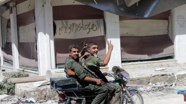 Syrian government forces flash the sign for victory as they patrol in the al-Khalidiyah district of Syria's central city of Homs by motorbike (AFP/JOSEPH EID)