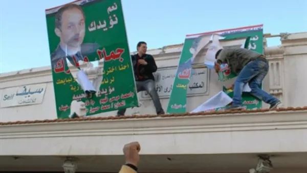 متظاهرون ينزعون صور نجل الرئيس مبارك في الاسكندرية/أ.ف.ب