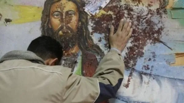 مسيحي قبطي يقف امام لوحة للمسيح عند كنيسة القديسين لطختها الدماء