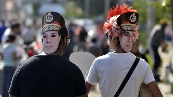 Egyptian opponents of deposed president Mohamed Morsi walk towards Tahrir Square in Cairo wearing cardboard cut-out masks of army chief General Abdel Fattah al-Sisi (AFP/MOHAMED EL-SHAHED)