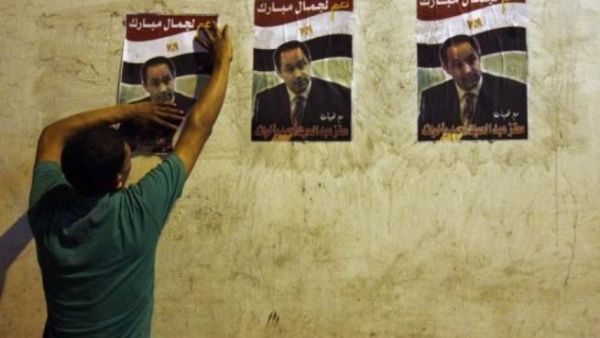 مصري يضعع ملصقات انتخابية لنجل الرئيس المصري جمال مبارك
