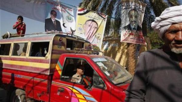 ناخبون يمرون أمام ملصقات لمرشحين في انتخابات مجلس الشعب بالاقصر في جنوب مصر