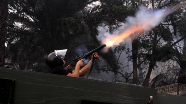An Egyptian riot policeman fires tear gas in Cairo, Egypt. [csgazette]