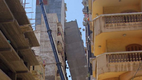 A high-rise apartment block in Egypt's second city Alexandria toppled across a street and was being propped up by another tall building on June 1, 2017. (AFP)