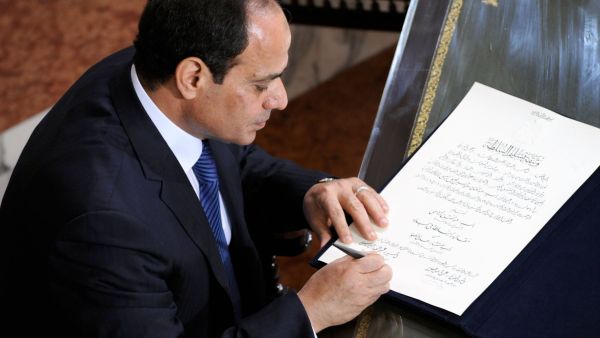 A handout picture made available on June 8, 2014 by the Egyptian presidency shows former army chief Abdel Fattah al-Sisi signing the handing over of power document from outgoing interim president Adly Mansour in Cairo. (AFP/Egyptian Presidency) 