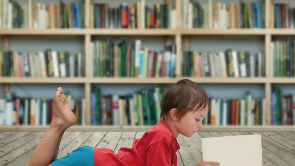 A child reads a book in a library. (Milan Bruchter / Shutterstock.com)