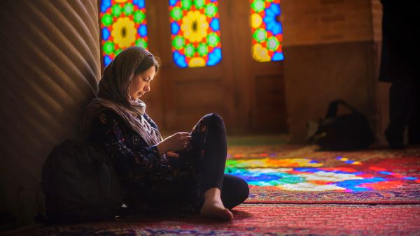 A girl reads inside an Iranian mosque. (fotosaga / Shutterstock.com)