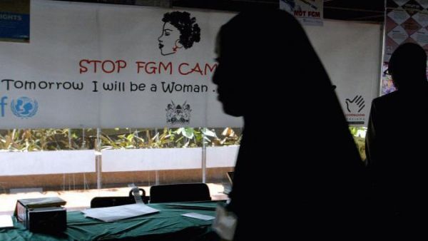 A young woman walks past a banner against female genital mutilation (FGM) at a conference in Nairobi (AFP)