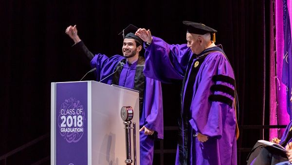 فؤاد حسن، المتحدث باسم طلاب الجامعة في حفل التخرج  وإيفيرت دينيس، عميد جامعة نورثويسترن في قطر  يؤدون هتاف الجامعة.