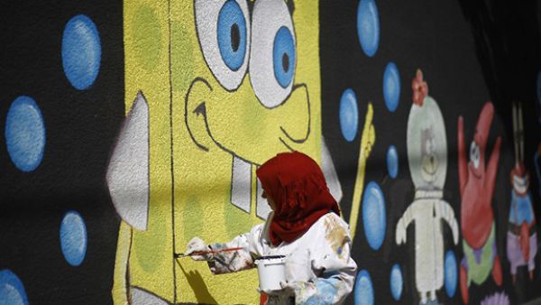 A Palestinian artist paints murals on the walls of a school run by the United Nations Relief and Works Agency for Palestine refugees (UNRWA) in Gaza City. (AFP/File)