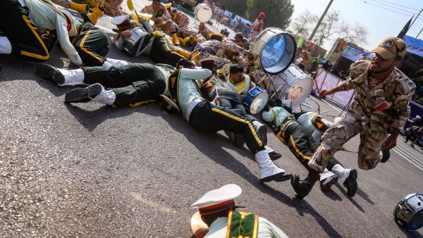 On September 22, 2018 in the southwestern Iranian city of Ahvaz shows a soldier running past injured comrades lying on the ground at the scene of an attack on a military parade. (AFP/File)