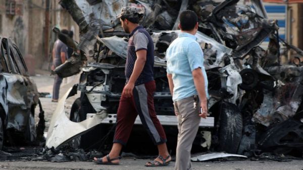 Iraqi men stand next to the wreckage of vehicles in the aftermath of a car bombing at a popular market in Baghdad's northern Shiite district of Sadr City. (AFP/Haidar Mohammed Ali)