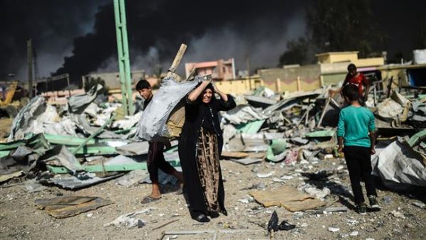An Iraqi woman and children collect wood and metal at a site, which was targeted by an airstrike a couple of days ago, in Qayyarah region south of Mosul, on October 29, 2016. (AFP/File)