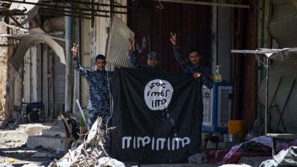 Iraqi government forces flash the sign for victory while holding a Daesh flag in western Mosul's Zanjili neighbourhood on June 9, 2017, during ongoing battles to try to take the city from Islamic State (IS) group fighters. (Mohamed El-Shahed/AFP)