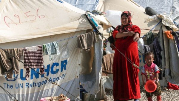 A displaced Iraqi woman and child, who fled the violence in the northern city of Mosul walk by the tents at the Hasan Sham camp on February 11, 2017 east of Erbil. (AFP/Safin Hamid)