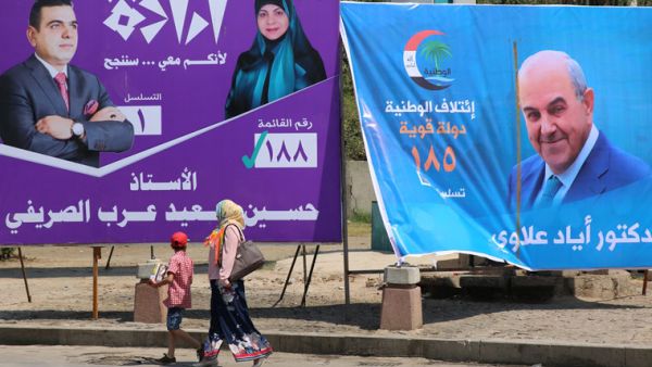 People walk past campaign posters of former Prime Minister Eyad Allawi and other candidates ahead of the upcoming parliamentary elections in Iraq. (AFP/ File Photo)