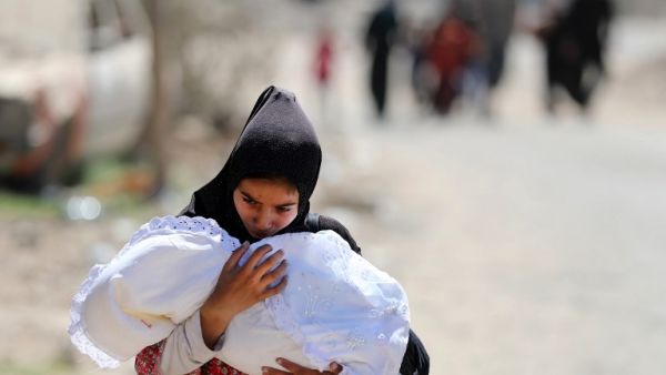 A displaced Iraqi woman carries a baby as she evacuates from western Mosul's Zanjili neighbourhood on June 1, 2017 during ongoing battles between Iraqi forces to retake the city from Daesh fighters. (Karim Sahib/AFP)