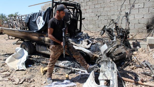 A member of Iraqi forces examines a burnt car with a Daesh flag in Hit, in the Anbar province. (AFP/Moadh Al-Dulaimi)