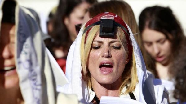 A Jewish female activist (C) from the Women of the Wall prayer rights group wears a prayer shawl and tefillin during a monthly prayer session near the Western Wall plaza in Jerusalem. (Twitter/Jpost)